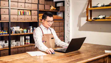 Tailor uses computer while standing in his shop