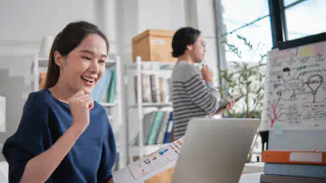 Woman sits at desk and looks at laptop