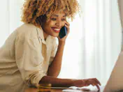 Woman talks on the phone while using a laptop